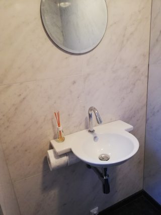 Hoogglans vloertegel 60×60 cm Marmerlook Bianco Carrara C108 geplaatst op het toilet.